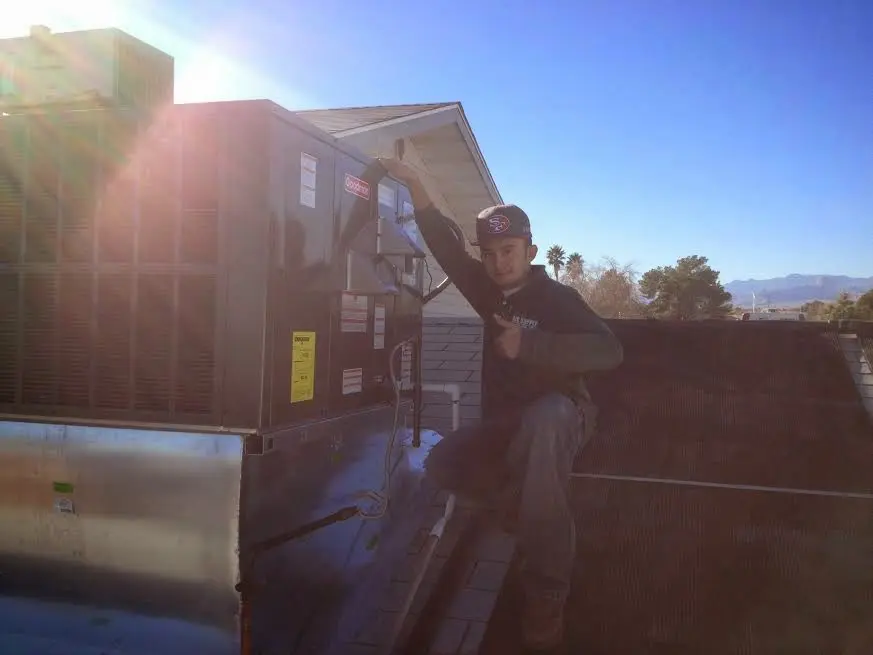 HVAC technician performing Heat Pump Repair on a rooftop unit in Highland